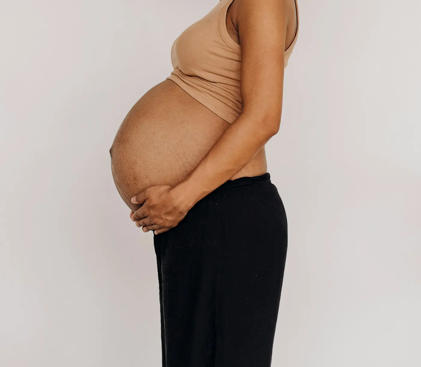 Grávida de perfil com as mãos sobre a barriga